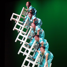 Peking Acrobats stacked up in a tall formation with chairs.