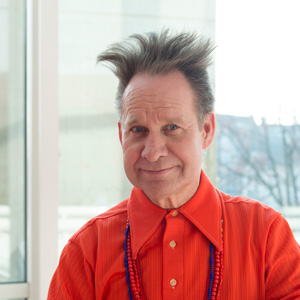 Photo of Peter Sellars in a red collared shirt in front of a window