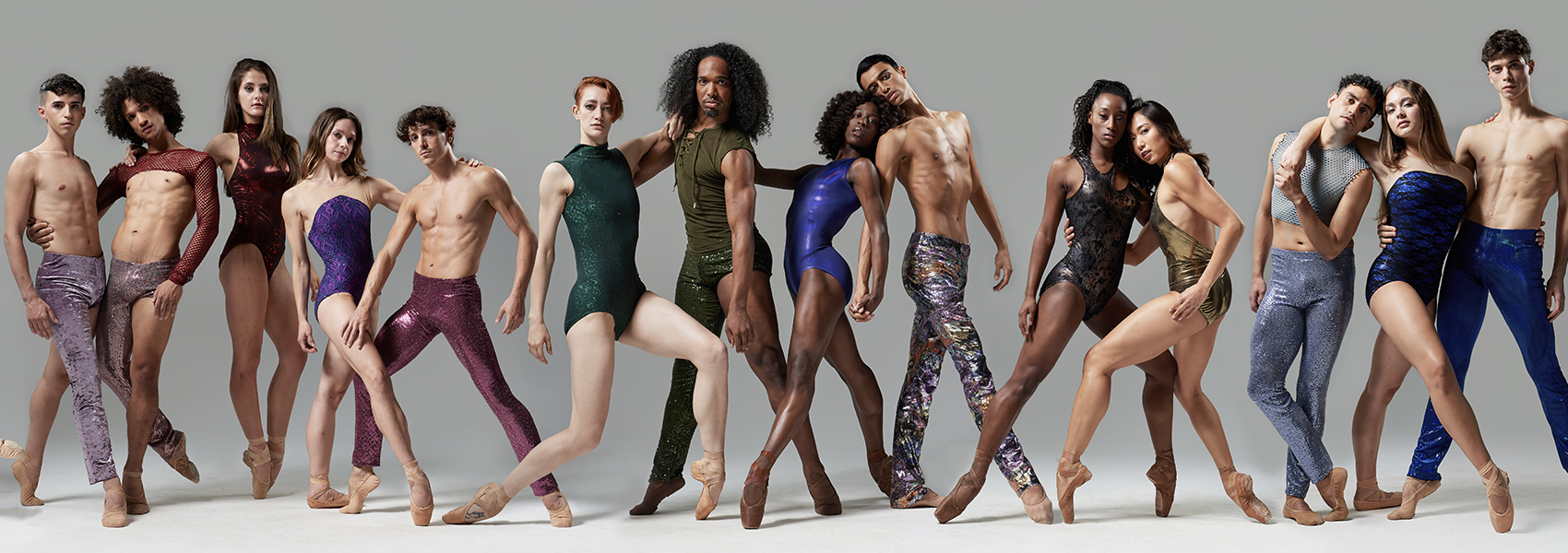 The Complexions dance troupe is pictured standing. They are posing in sequined pants and leotards of various colors.