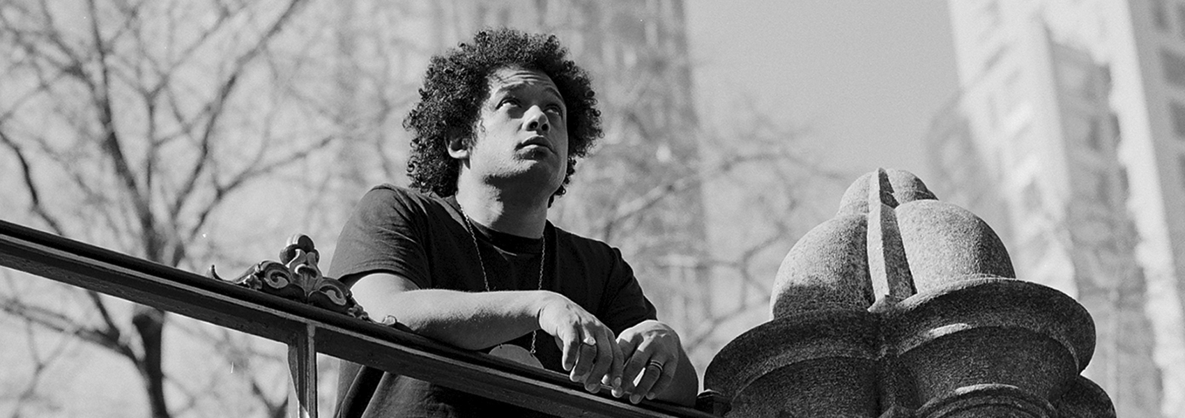 Makaya McCraven is pictured standing on a bridge with his hands on the railing in a black and white photograph.