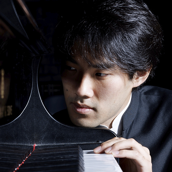 Pianist Bruce Liu is pictured with his chin resting on a piano.