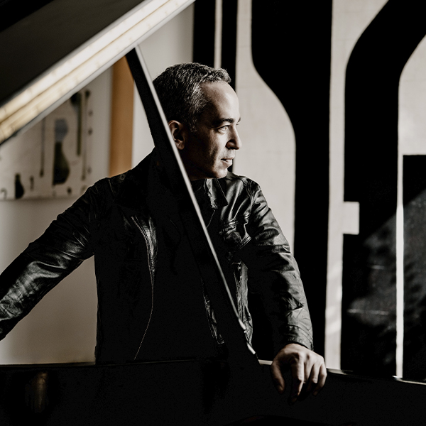 Inon Barnatan stands near a concert grand piano